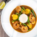 Portrait overhead image of a Thai Prawn Massaman Curry with potatoes and green beans served in a white bowl