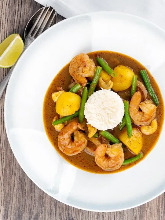 Portrait overhead image of a Thai Prawn Massaman Curry with potatoes and green beans served in a white bowl