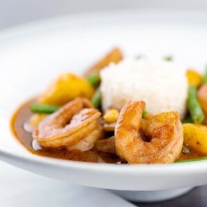 Square image of a Thai Prawn Massaman Curry with potatoes and green beans served in a white bowl