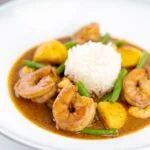 Portrait image of a Thai Prawn Massaman Curry with potatoes and green beans served in a white bowl