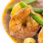 Portrait close up image of a Thai Prawn Massaman Curry with potatoes and green beans served in a white bowl