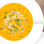 Portrait overhead image of a spicy carrot and lentil soup spiced with harissa paste and garnished with a swirl of tahini served in a white bowl featuring a title overlay