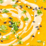 Portrait close up image of a spicy carrot and lentil soup spiced with harissa paste and garnished with a swirl of tahini featuring a text overlay