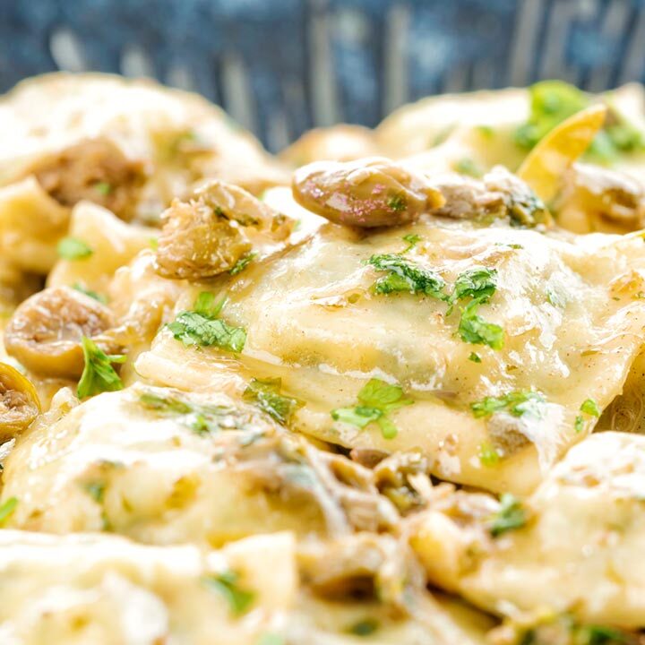 Square close up image of homemade spinach and ricotta ravioli with a lemon caper butter sauce