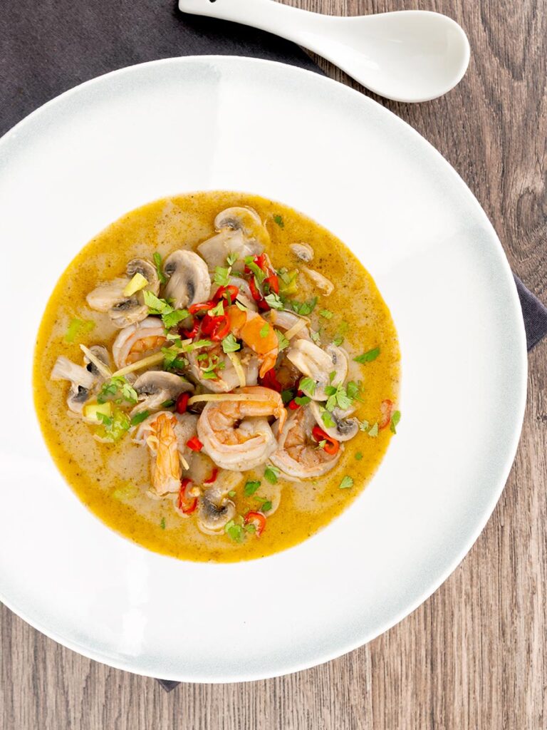 Portrait overhead image of a Thai Prawn Tom Yom Soup served in a white soup bowl