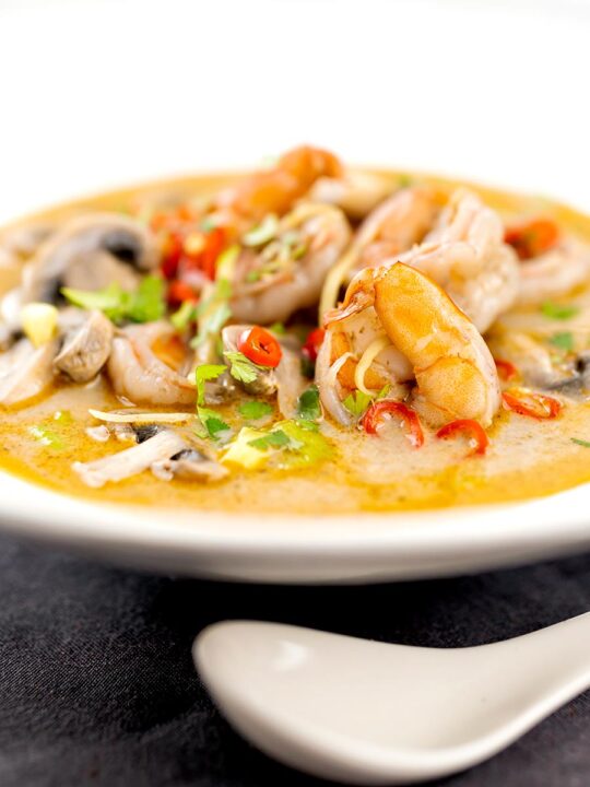 Portrait image of a Thai Prawn Tom Yom Soup served in a white soup bowl