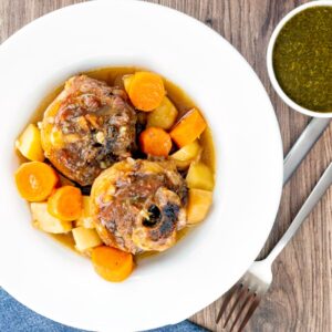 Square overhead image of a lamb neck stew using bone in lamb neck chops, potatoes, carrots and parsnips served in a white bowl