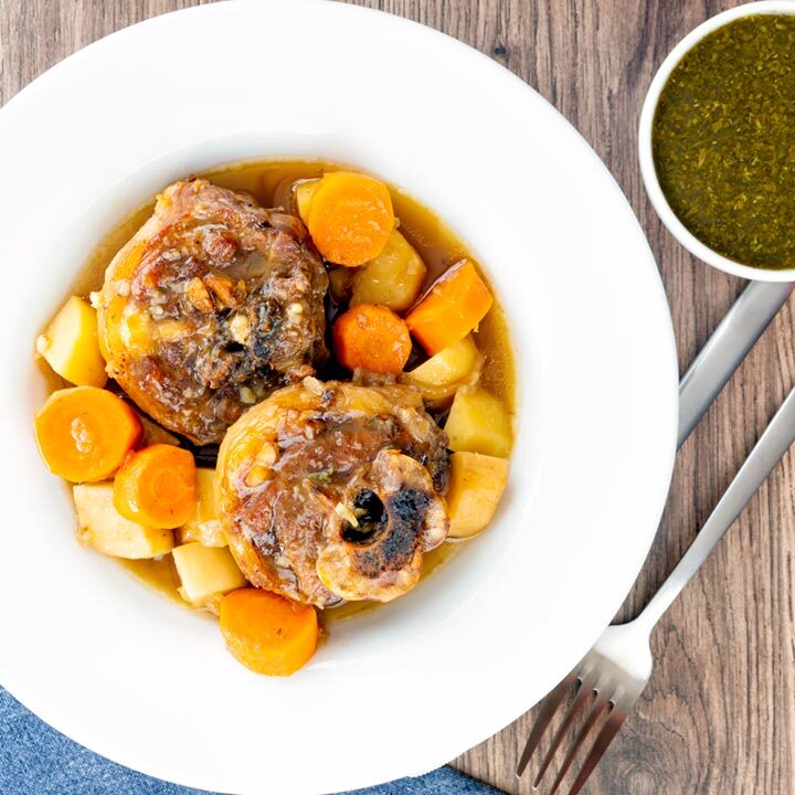 Square overhead image of a lamb neck stew using bone in lamb neck chops, potatoes, carrots and parsnips served in a white bowl