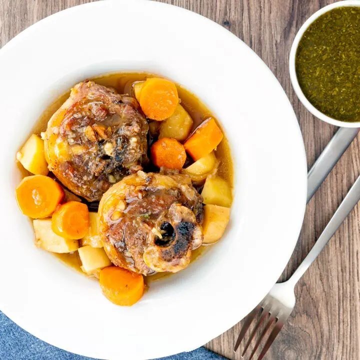 Square overhead image of a lamb neck stew using bone in lamb neck chops, potatoes, carrots and parsnips served in a white bowl