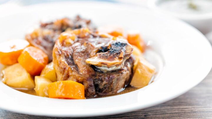Landscape image of a lamb neck stew using bone in lamb neck chops, potatoes, carrots and parsnips served in a white bowl