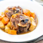 Portrait image of a lamb neck stew using bone in lamb neck chops, potatoes, carrots and parsnips served in a white bowl