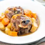 Portrait image of a lamb neck stew using bone in lamb neck chops, potatoes, carrots and parsnips served in a white bowl