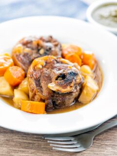 Portrait image of a lamb neck stew using bone in lamb neck chops, potatoes, carrots and parsnips served in a white bowl