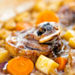 Portrait close up image of a lamb neck stew using bone in lamb neck chops, potatoes, carrots and parsnips featuring a title overlay