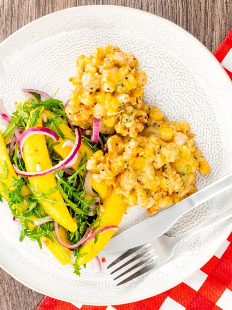 Portrait overhead image of prawn fritters with sweetcorn and spring onion served with a mango salad
