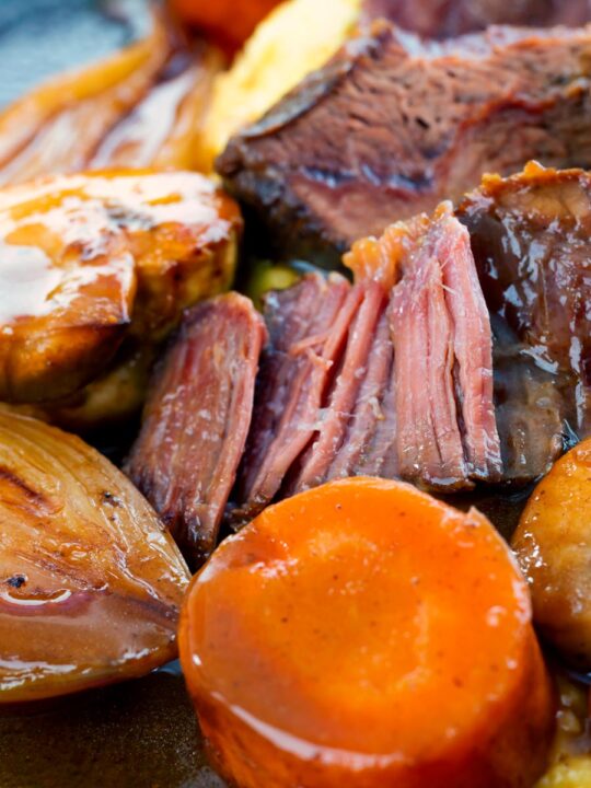 Portrait close up image of beer braised beef cheeks with carrot, shallot and mushrooms