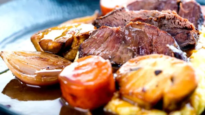 Landscape image of beer braised beef cheeks with carrot, shallot and mushrooms served on mashed potato