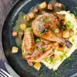 Braised pheasant casserole with a cider gravy, bacon & apples served with mashed potatoes featuring a title overlay.