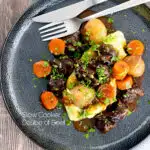 Portrait overhead image of a slow cooker beef daube featuring carrots and whole small onions, served with mashed potato and garnished with parsley featuring a title overlay