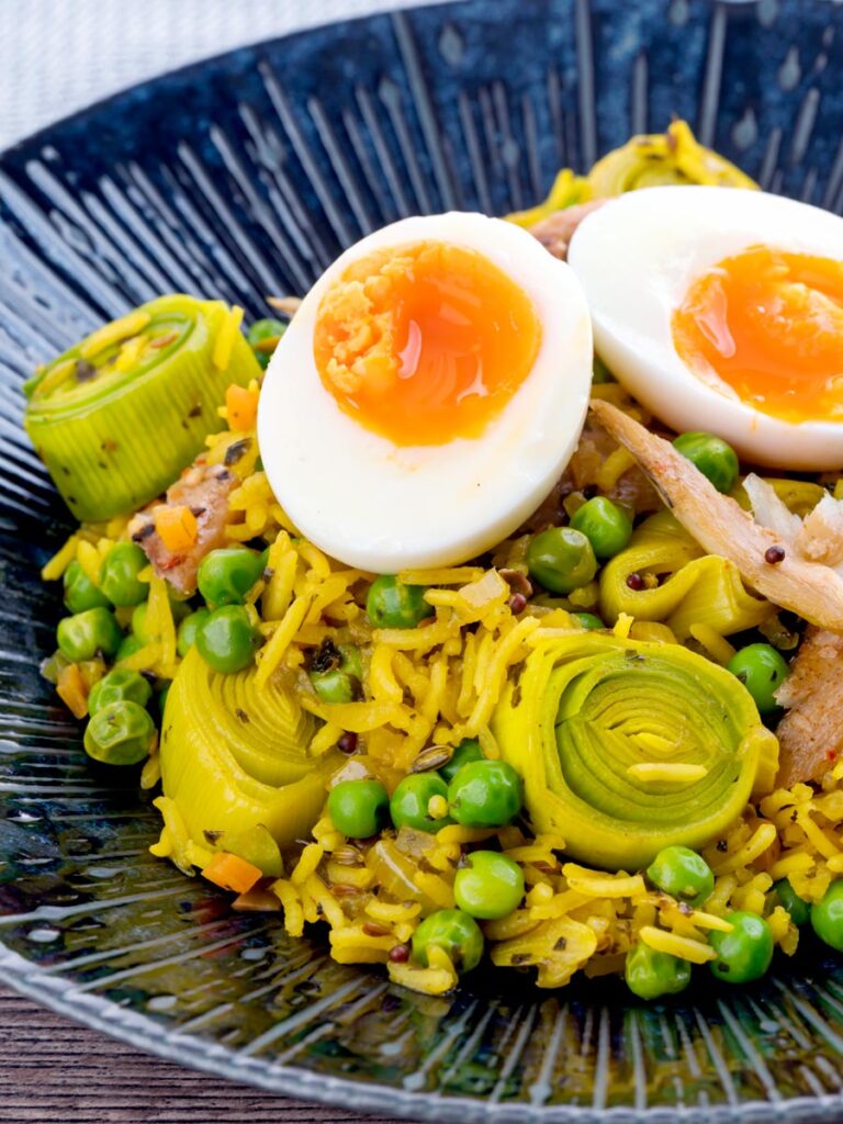 Portrait image of an Indian inspired smoked mackerel kedgeree with boiled eggs and leeks