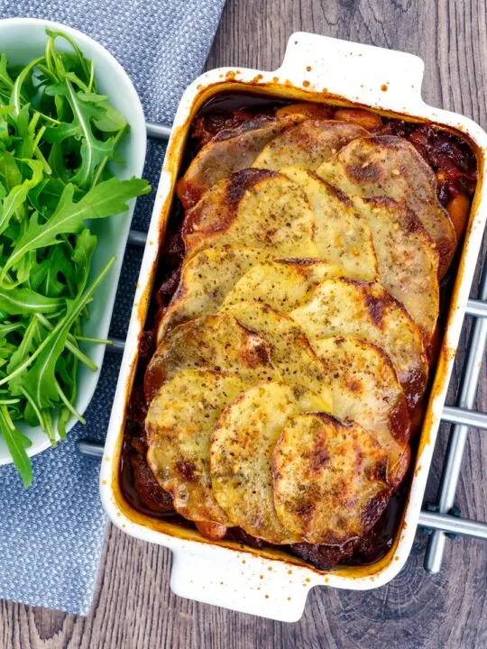 Portrait overhead image if a sliced potato topped spicy beef hotpot served in a gratin bowl