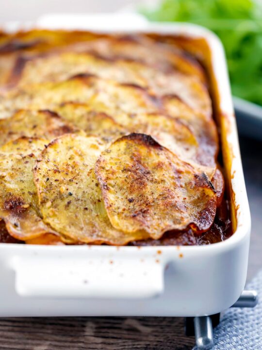 Portrait image if a sliced potato topped spicy beef hotpot served in a gratin bowl