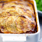 Portrait image if a sliced potato topped spicy beef hotpot served in a gratin bowl featuring a title overlay