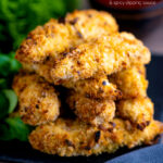 A pile chicken goujons in a hazelnut and breadcrumb with a spicy dipping sauce in the background featuring a title overlay