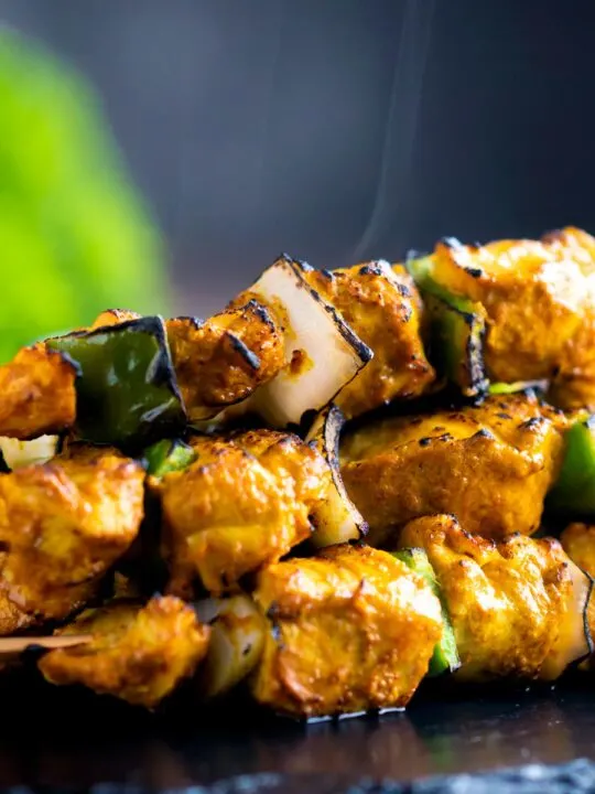 Close up steaming hot Chicken tikka kebabs with onion and green pepper
