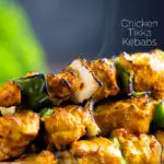 Close up steaming hot Chicken tikka kebabs with onion and green pepper featuring a title overlay