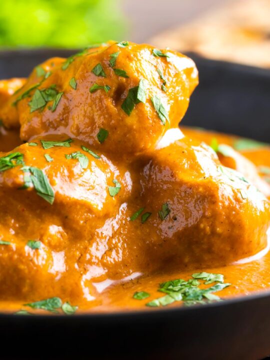 Close up creamy rich chicken tikka masala curry in an iron karai