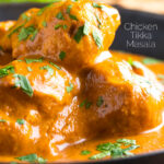 Close up creamy rich chicken tikka masala curry in an iron karai featuring a title overlay