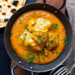 Creamy rich chicken tikka masala curry in an iron karai served with chapati