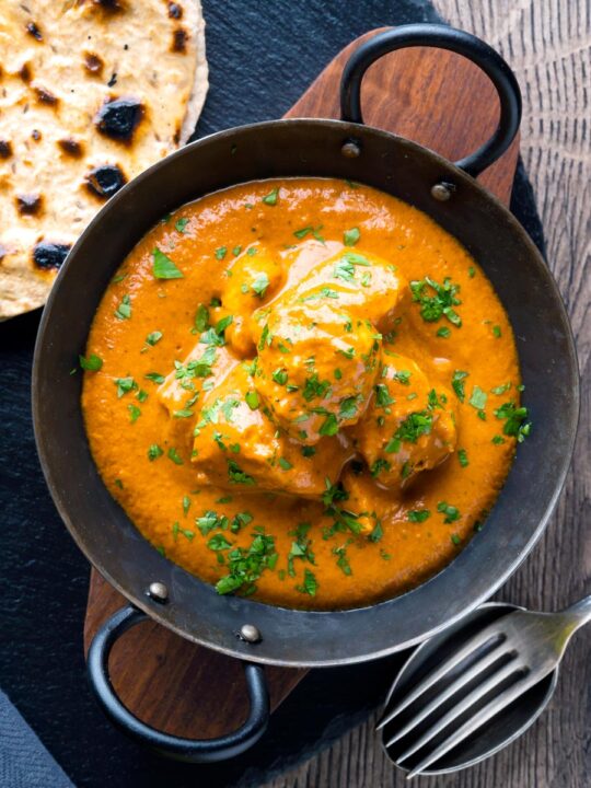 Creamy rich chicken tikka masala curry in an iron karai served with chapati