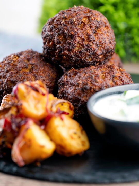 Nargis kebab or Indian Scotch eggs served with Bombay potatoes and cucumber raita
