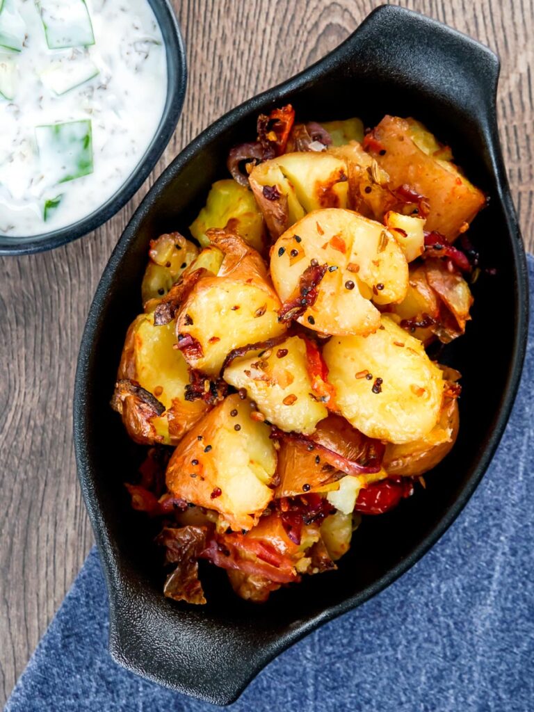 Overhead Roast Bombay potatoes or Bombay aloo served with cucumber raita