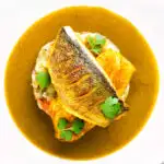 Overhead sea bass fillet curry served with fenugreek potatoes featuring a title overlay