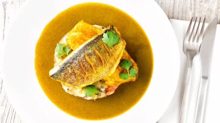 Overhead sea bass curry featuring turmeric fish fillets and tamarind curry sauce