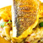 Close up Sea bass curry featuring a tamarind curry sauce & Fenugreek potatoes
