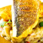 Close up Sea bass curry with a tamarind curry sauce & Fenugreek potatoes featuring a title overlay