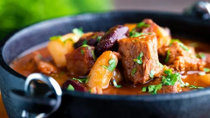 Close up babgulyas, a Hungarian bean goulash served in a cast iron bowl.