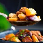 Steaming hot spoonful of Babgulyas, a Hungarian bean goulash taken from an iron bowl.