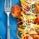 Overhead tomato and bacon pasta garnished with parsley and pecorino cheese served on a blue plate featuring a title overlay.