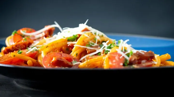 Tomato and bacon pasta garnished with parsley and pecorino cheese.