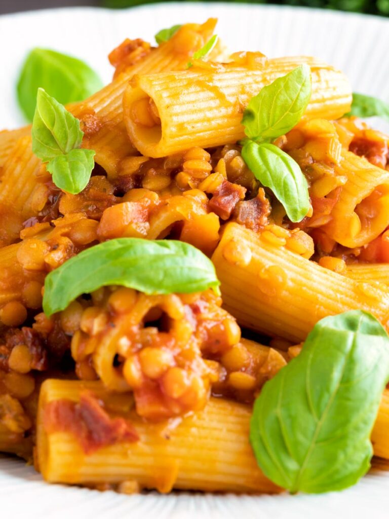 Close up of a red lentil ragu or bolognese served with rigatoni pasta.