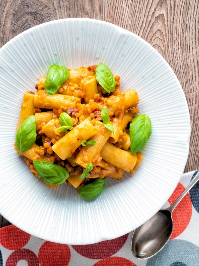 Overhead of a red lentil ragu or bolognese served with rigatoni pasta.