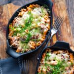 Individual meatball pasta bake with a cheesy topping served in stoneware bowls.