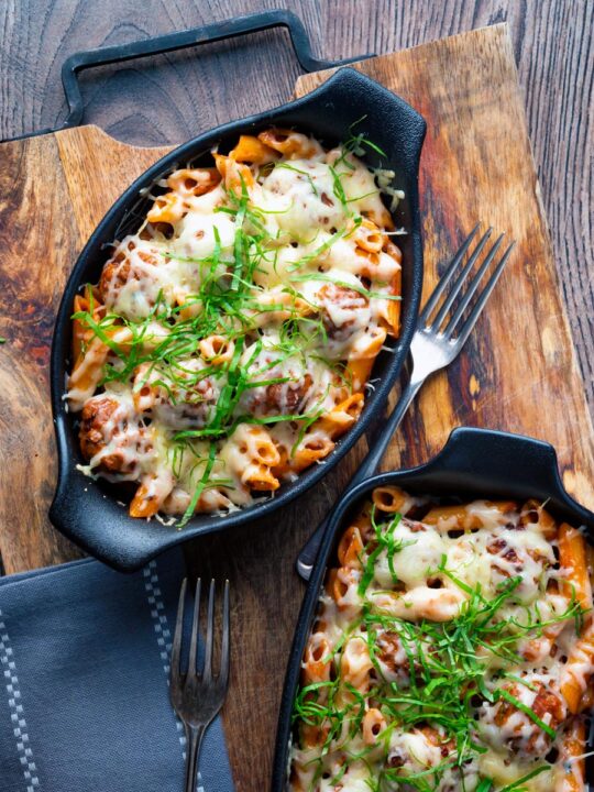 Individual meatball pasta bake with a cheesy topping served in stoneware bowls.
