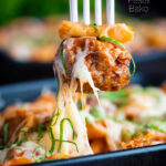 Meatball being removed from a cheesy meatball pasta bake with a fork featuring a title overlay.