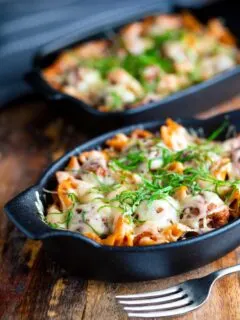 Cheesy meatball pasta bake served in individual stoneware bowls.